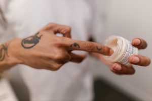 Close-up of Person Applying Cream from Bottle