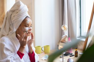 Woman in a White Bathrobe and Head Towel Applying Face Cream