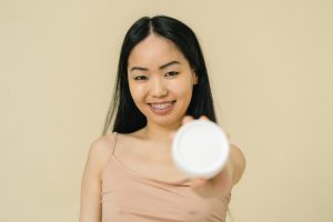 Woman with braces holding plastic box of cream in hand